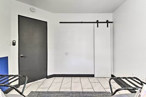 Ein Zimmer mit einer dunklen Tür, einer Schiebetür und zwei Metallstühlen mit Kissen.