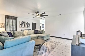 Ein modernes Wohnzimmer mit einem Ecksofa, einem runden Couchtisch und einem Deckenventilator.