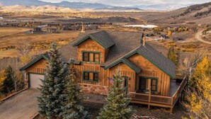A rustic log cabin with a stone foundation, a wooden deck, and a view of a mountainous landscape. - Private Hot Tub: Scenic Granby Vacation Rental! (Granby)