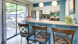 A modern kitchen with a bar area, a refrigerator, microwave, and a sink. - Families w/ Pets! Lake-view Osage Beach Home (Osage Beach)