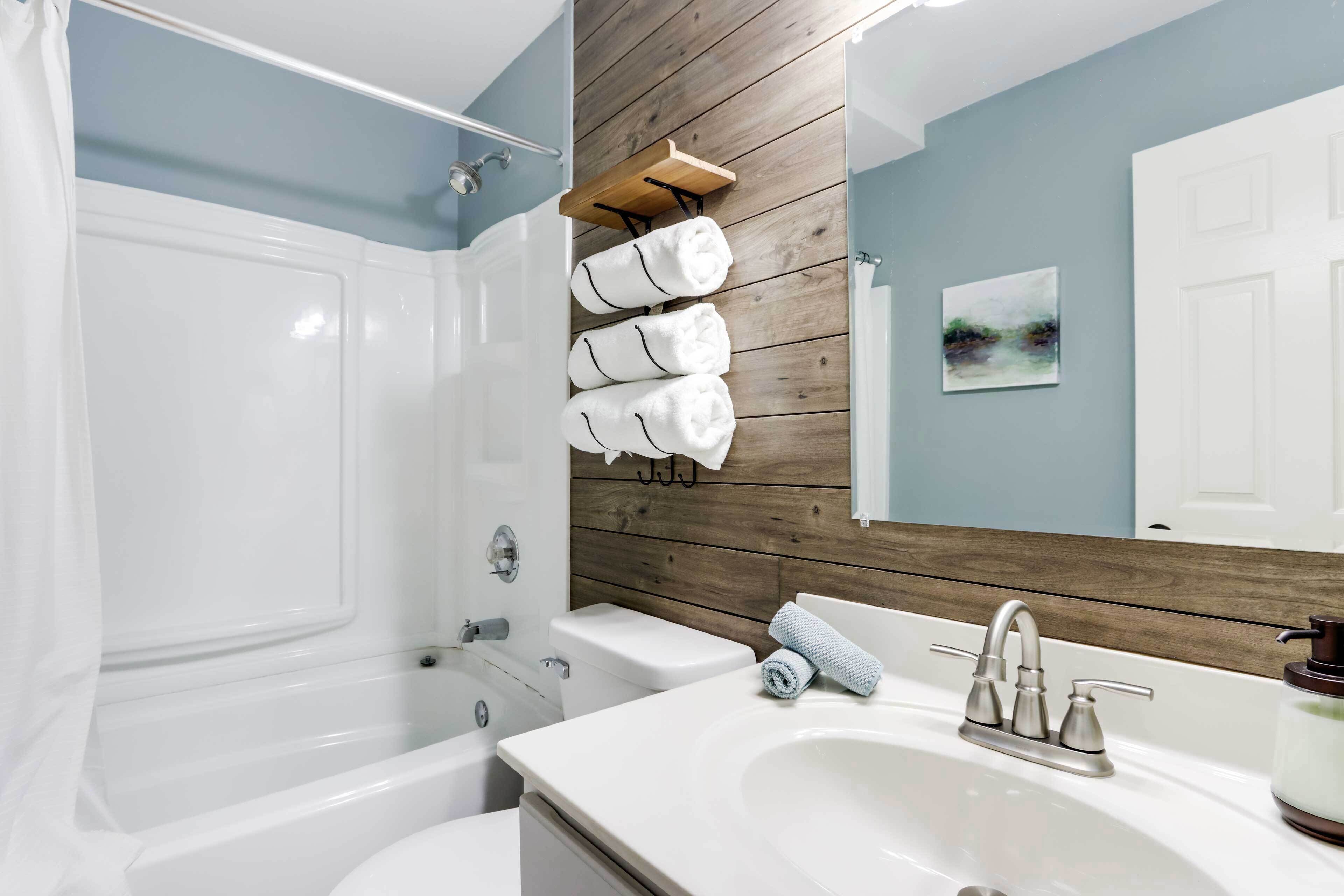 Ein Badezimmer mit Badewanne, Toilette, Waschbecken und einer Holzverkleidung.