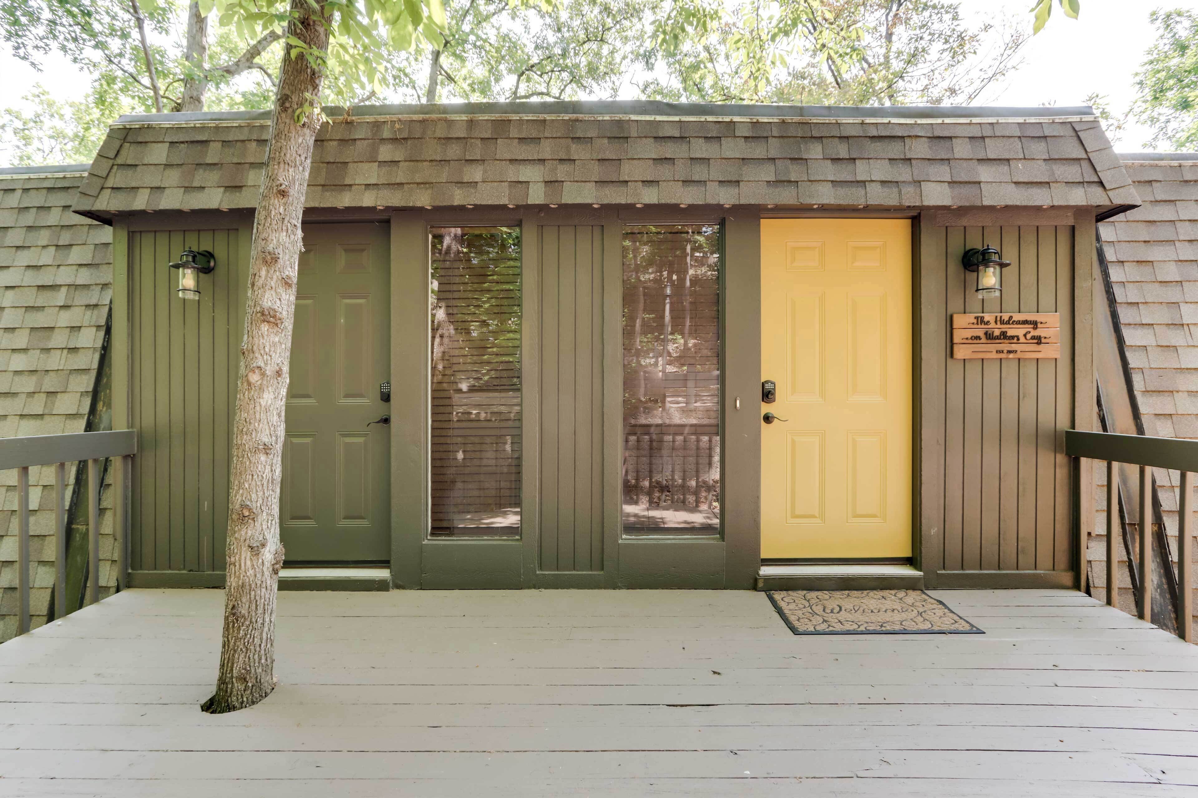 Une cabane en bois avec deux portes, une verte et une jaune, et une enseigne sur laquelle on peut lire : « Le Refuge secret sur l’île sauvage et merveilleuse ».