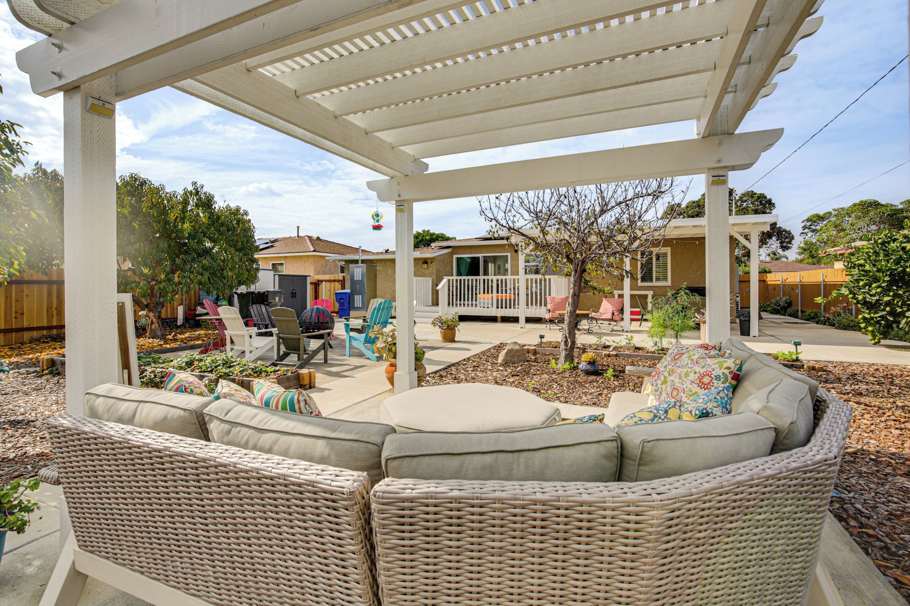 Un patio cubierto con mobiliario de mimbre y una pérgola blanca.