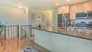Una cocina moderna con encimeras de granito, electrodomésticos de acero inoxidable y armarios de madera.