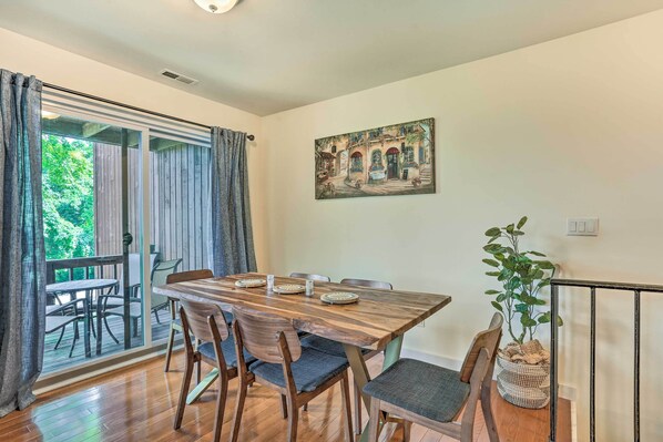A dining area with a wooden table and chairs, a painting on the wall, and a view through the glass door. - Sun-lit Vernon Condo < 2 Mi to Ski Resort! (Vernon)