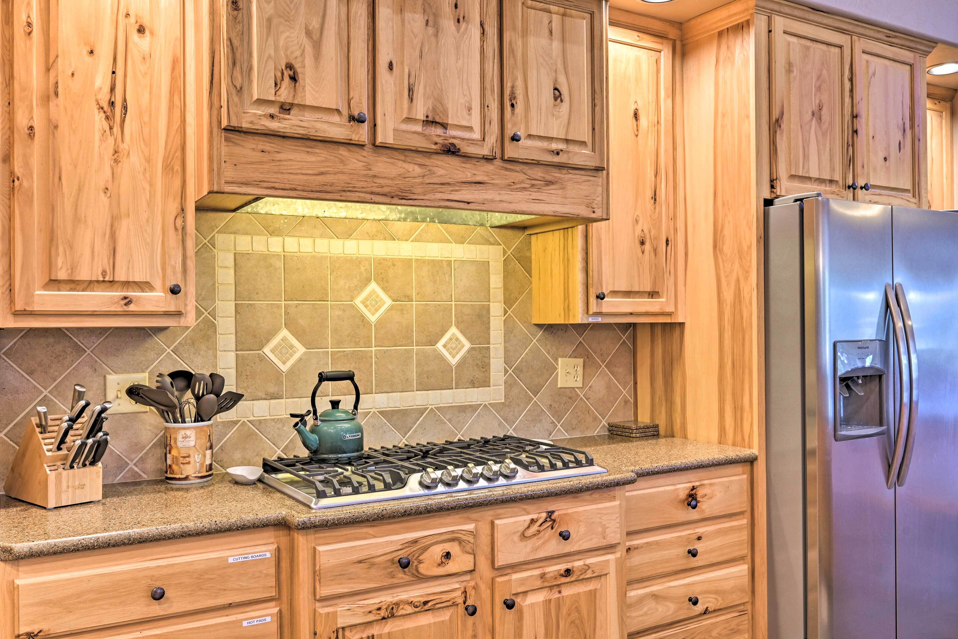 A kitchen with wooden cabinets, a gas stove, a stainless steel refrigerator, and a tiled backsplash.