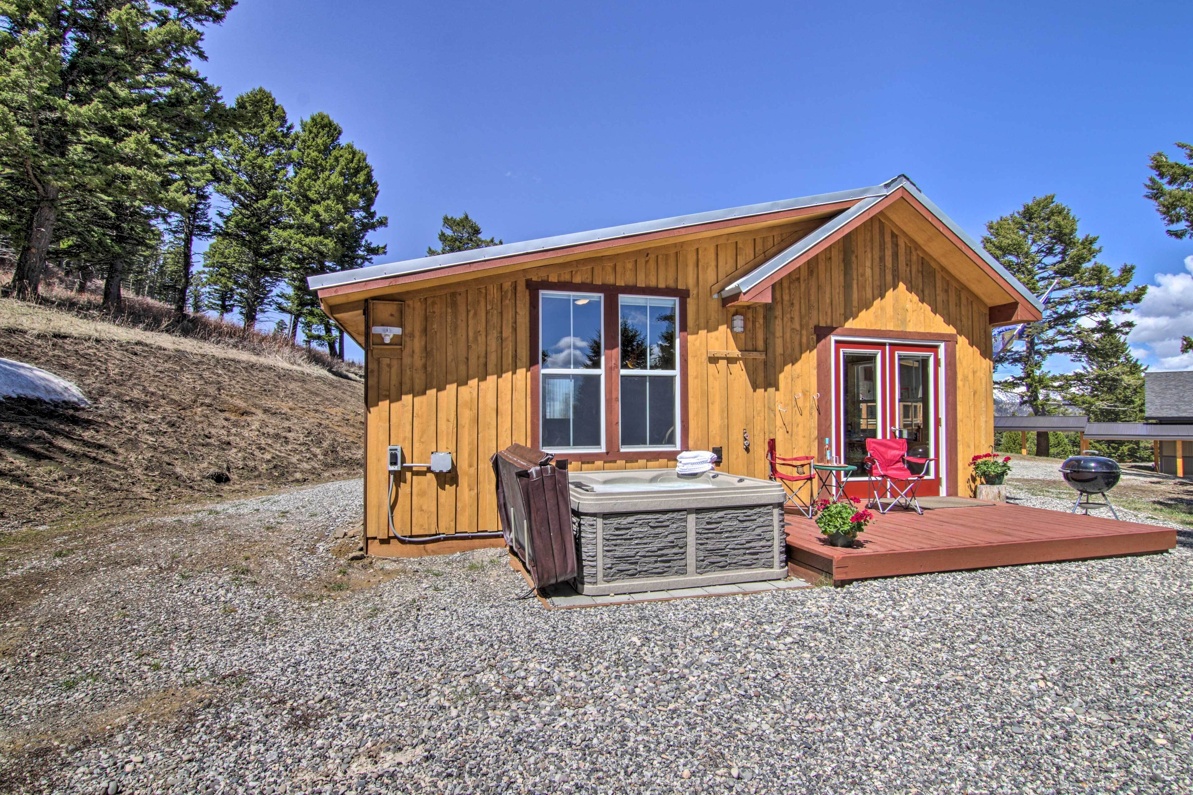 A wooden cabin with a hot tub, deck, and barbecue area.