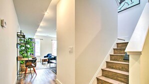 Et moderne interiør med trappe, trægulv og et spiseområde med stole og et bord.