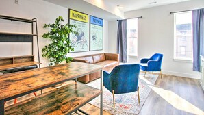 Et moderne mødelokale med et træbord, blå stole, en brun sofa og en stor plante.