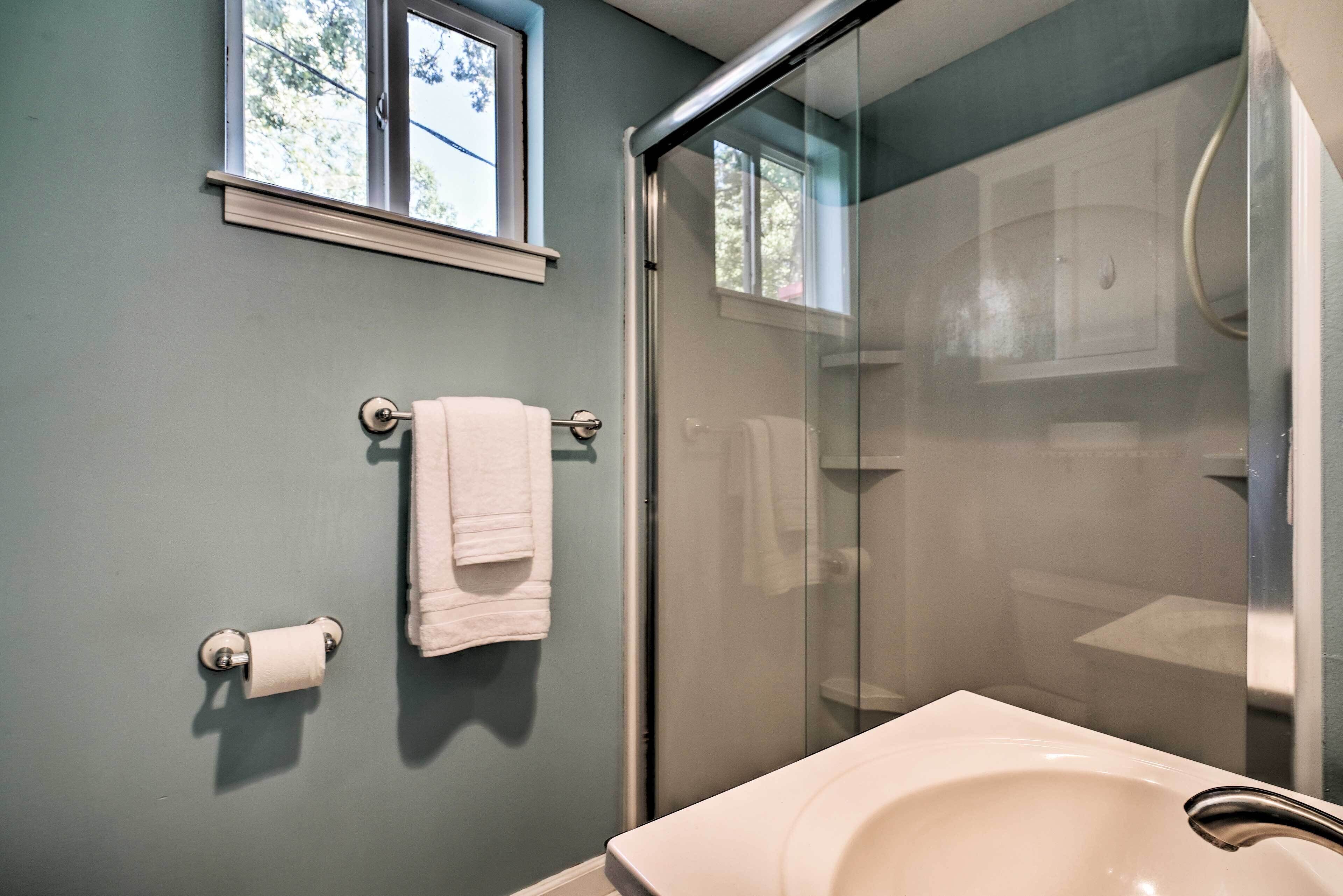 Une salle de bain avec une douche à parois de verre, un lavabo et une fenêtre située au-dessus du miroir.