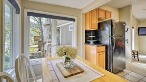 Una cucina con tavolo in legno, un frigorifero e una finestra che si affaccia sull'esterno.