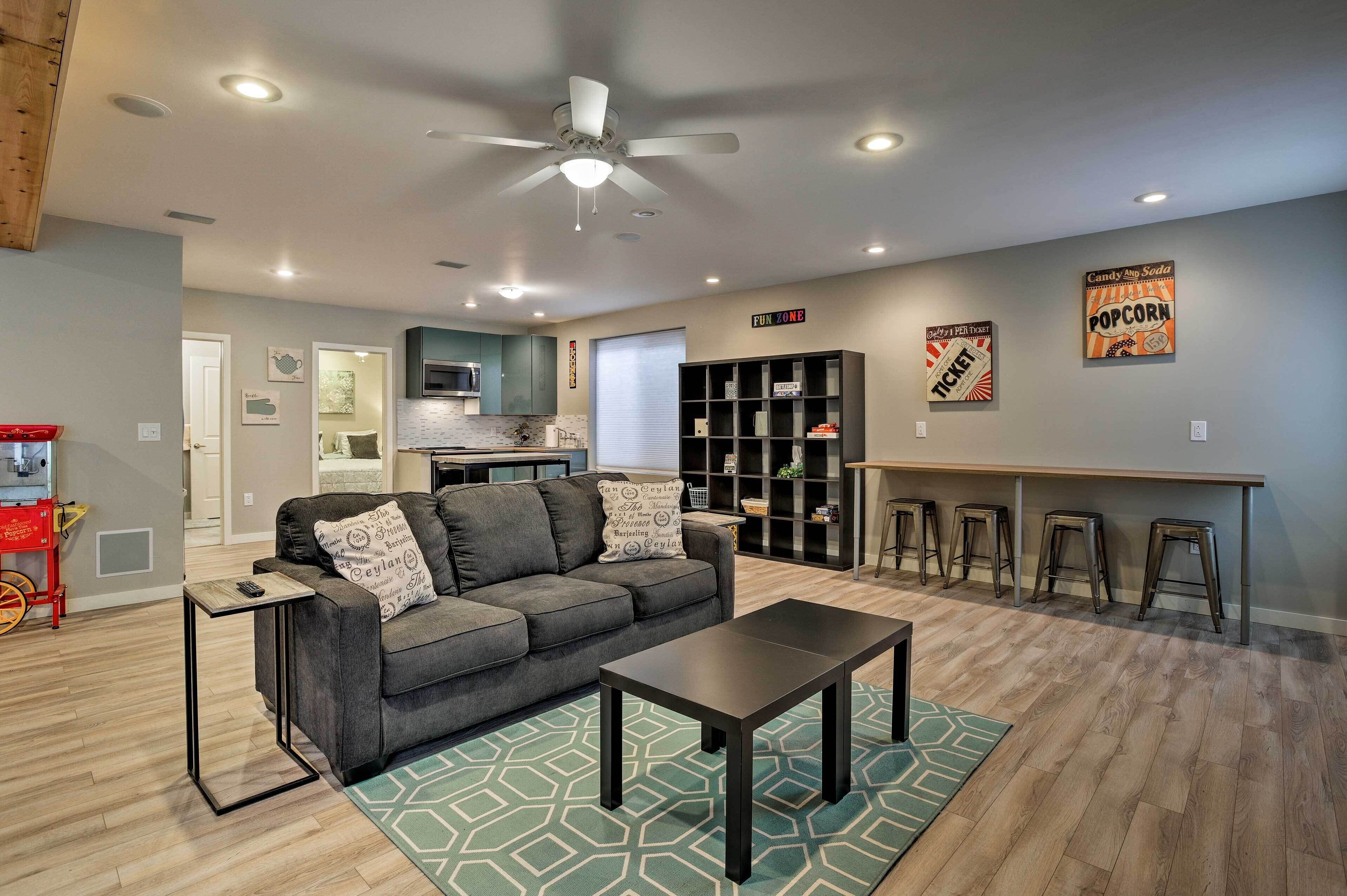 A modern living room with a gray sofa, a coffee table, and a kitchen area in the background.