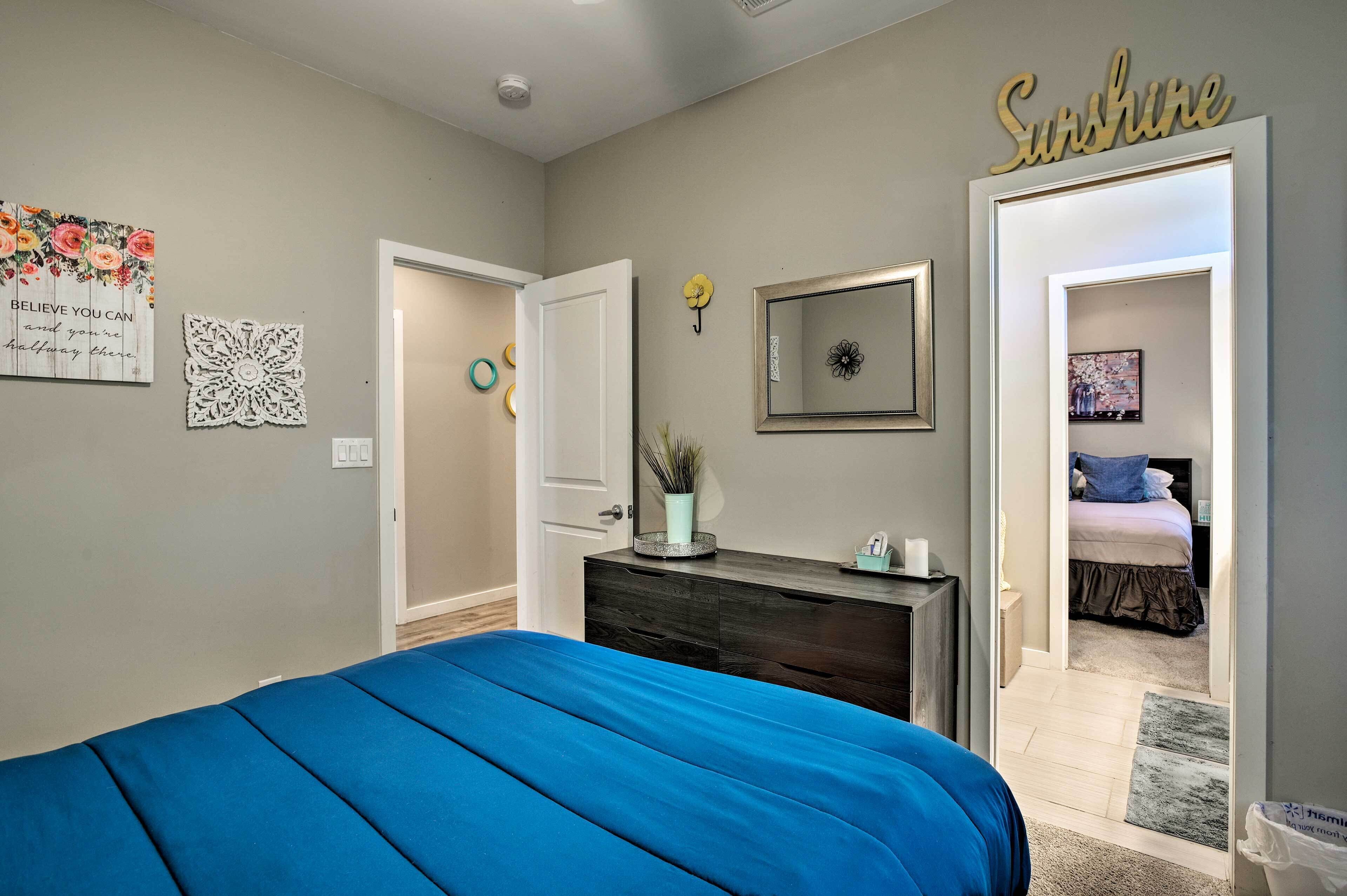 A bedroom with a bed, dresser, mirror, and a wall with a 'Sunshine' sign.