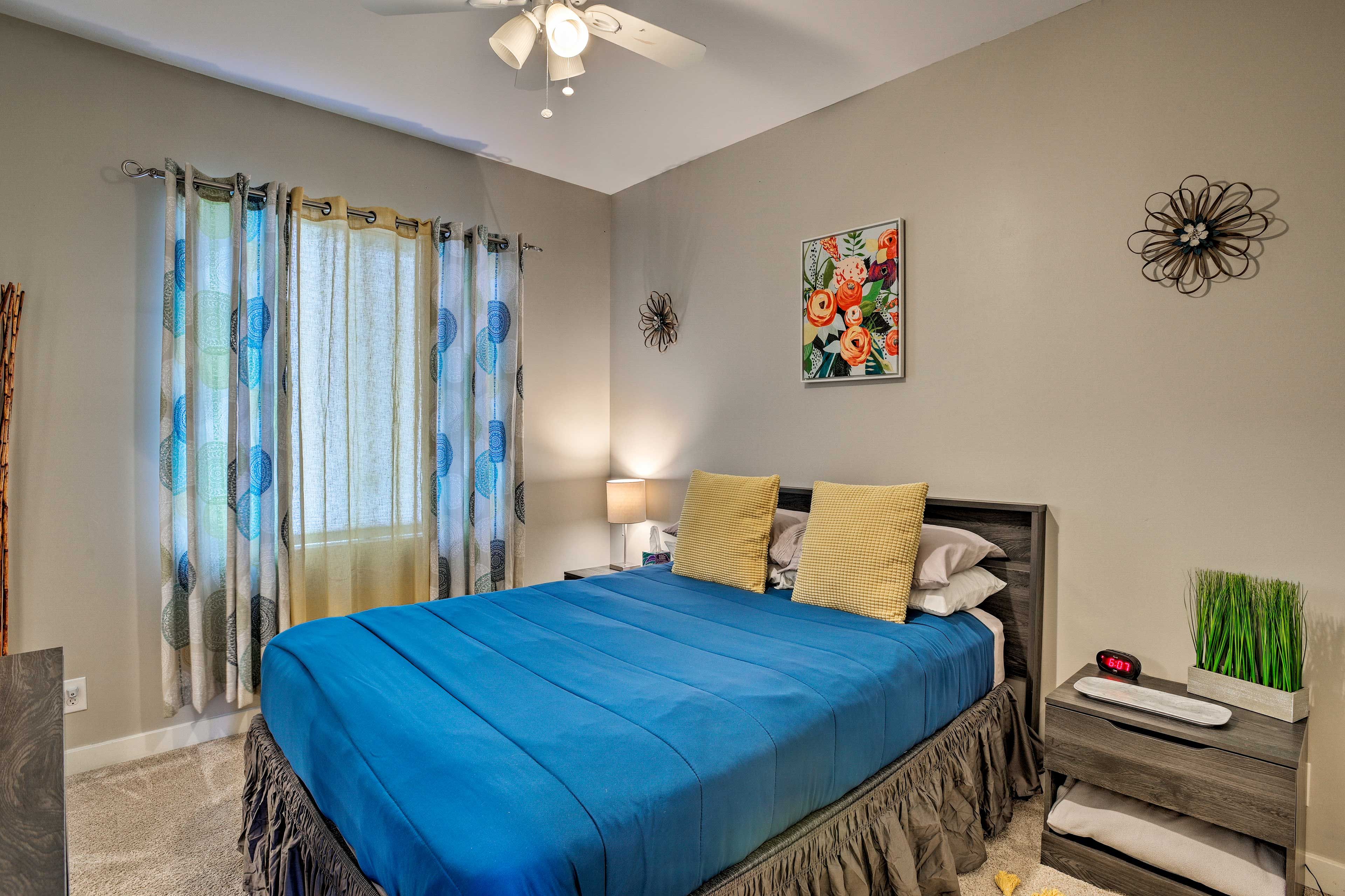 A bedroom with a bed, a nightstand, a lamp, a wall clock, and a decorative wall piece.