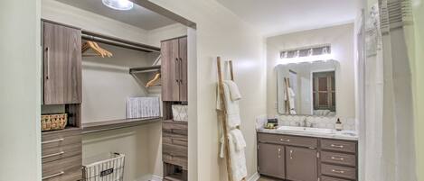 A modern bathroom with a vanity, mirror, and built-in storage.