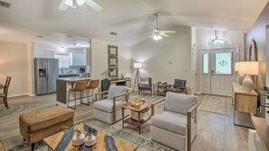 A spacious living area with a kitchen in the background, a dining area, and a seating area with a coffee table. - Cozy-modern Pensacola Home: Large Yard, Grill (Pensacola)