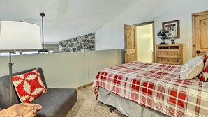 A bedroom with a bed, a chair, a lamp, a wooden dresser, and a stone wall. - All-season Resort Condo: 5 Mi to Dillon Reservoir (Silverthorne)