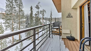 A balcony with a metal railing, a chair, a table, and a stack of firewood. - All-season Resort Condo: 5 Mi to Dillon Reservoir (Silverthorne)