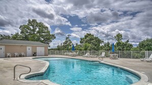 A swimming pool with a tiled edge, surrounded by lounge chairs and a fence. - Water Views + Pool Access: Lake Ozark Escape! (Lake Ozark)
