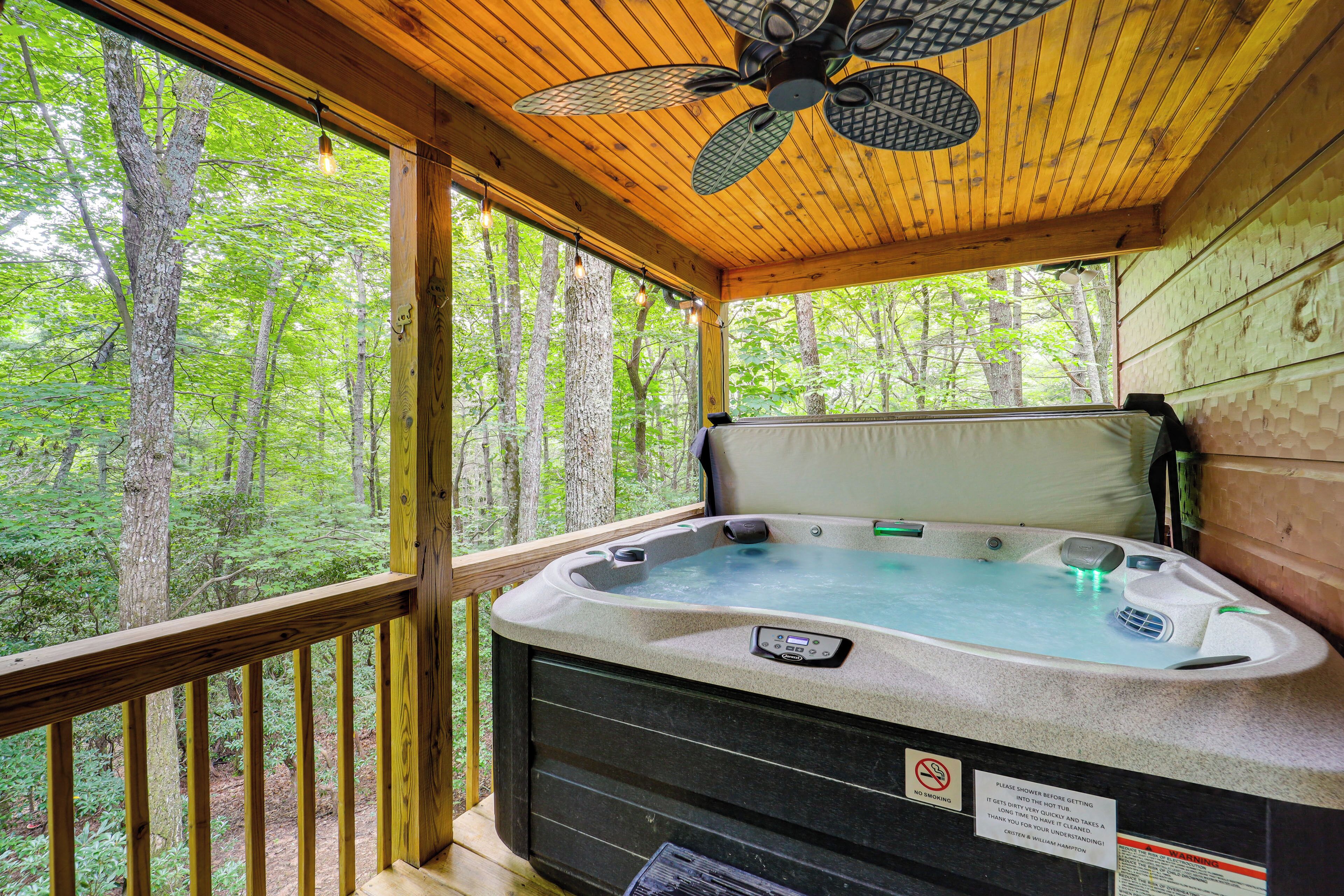 Ein Whirlpool auf einer Holzterrasse mit Blick auf einen Wald.