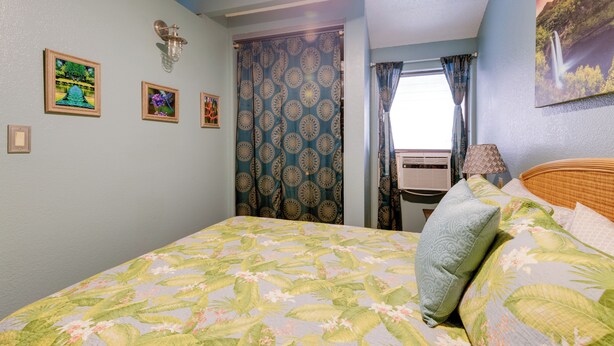 Una camera da letto con un letto, una finestra con tende e quadri appesi al muro.