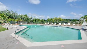 Una piscina rettangolare con acqua cristallina, circondata da poltroncine bianche e un cartello che indica divieto di balneazione.