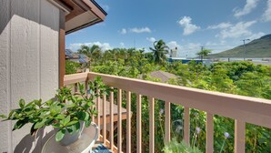 Un balcone con vista su un giardino rigoglioso e un corpo d'acqua in lontananza.