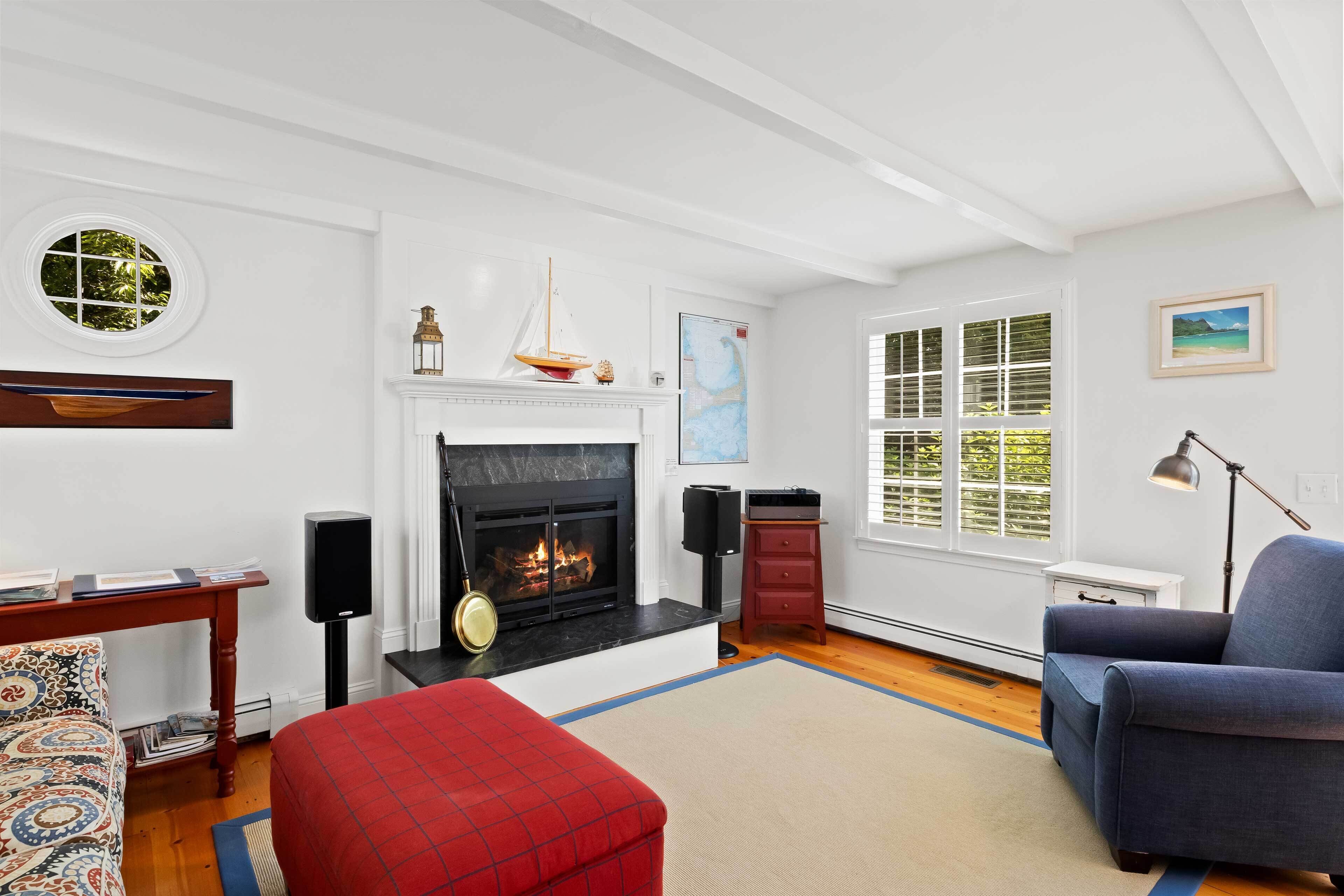 A living room with a fireplace, a round window, a sofa, and a side table.