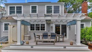 A two-story house with a covered patio area featuring outdoor furniture and a pergola. - 3 Bicycles Provided! Cape Cod Cottage w/ Deck (Orleans)