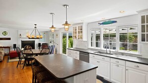 A modern kitchen with white cabinetry, a large island, and pendant lighting. - 3 Bicycles Provided! Cape Cod Cottage w/ Deck (Orleans)