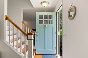 Una escalera con barandillas de madera y una puerta azul claro con paneles de vidrio.