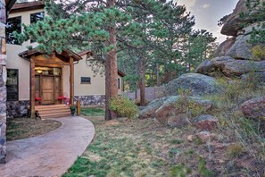 A house with a stone exterior, a wooden front door, and a stone pathway leading to the entrance. - Fall River Hideaway in Estes - 3 Mi to Nat'l Park! (Estes Park)