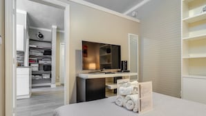 A hotel room with a bed, a desk with a mirror, a TV, and a walk-in closet. - Sunny Miami Beach Condo Steps to Boardwalk! (Miami Beach)