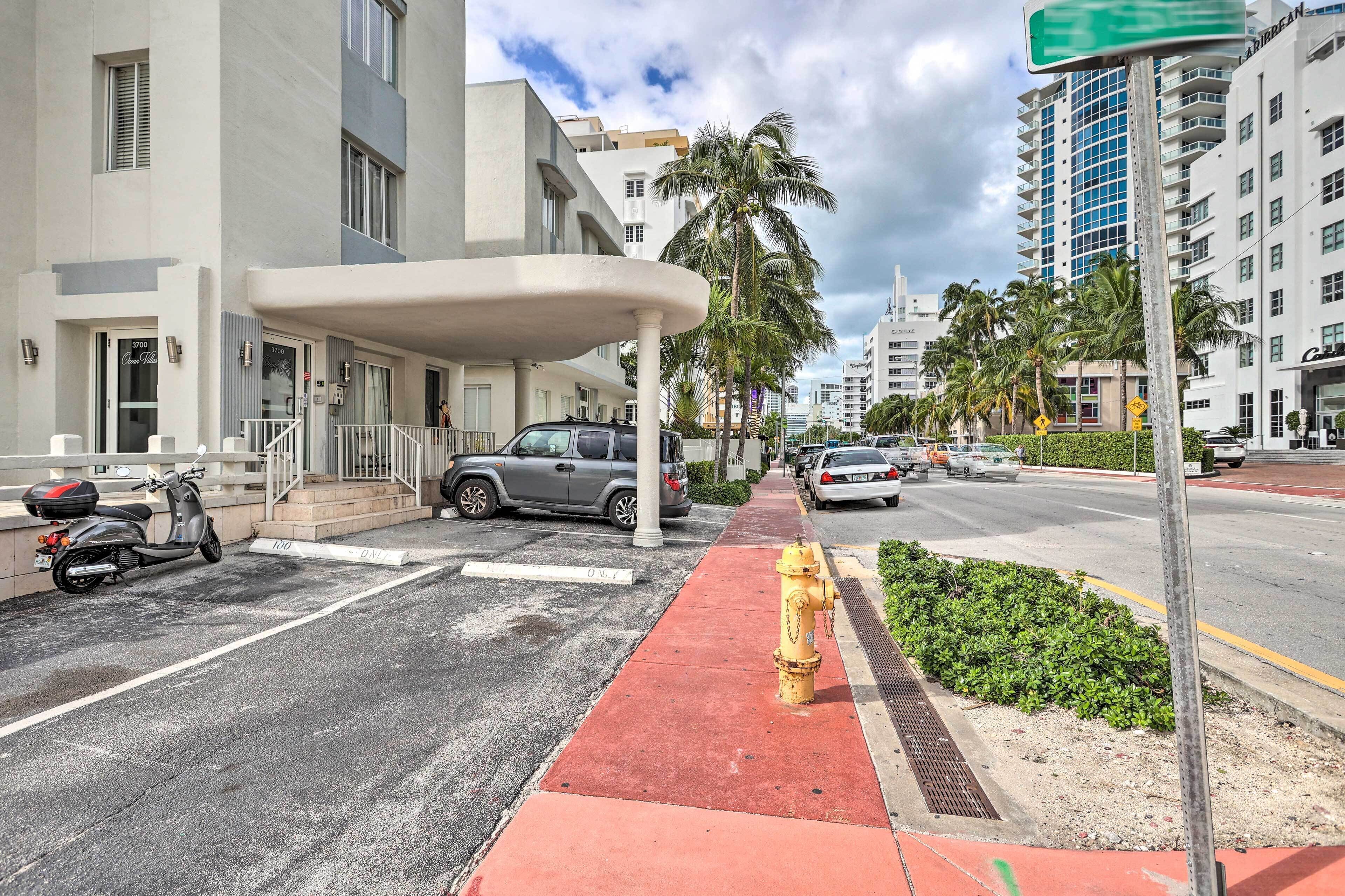A street view with a building entrance, parked vehicles, and a yellow fire hydrant.