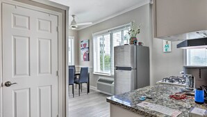 A modern kitchen with a granite countertop, stainless steel appliances, and a dining area with a table and chairs. - Sunny Miami Beach Condo Steps to Boardwalk! (Miami Beach)