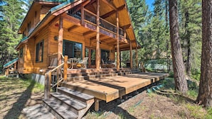 A wooden cabin with a balcony, a deck, and a staircase leading to the entrance. - Secluded Leavenworth Cabin on Chiwawa River! (Leavenworth)