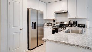 A modern kitchen with white cabinetry, stainless steel appliances, and a granite countertop. - Cozy Texas Escape Near Seaworld San Antonio! (San Antonio)