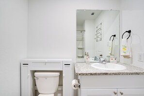 A bathroom with a white toilet, a sink, and a mirror. - Cozy Texas Escape Near Seaworld San Antonio! (San Antonio)