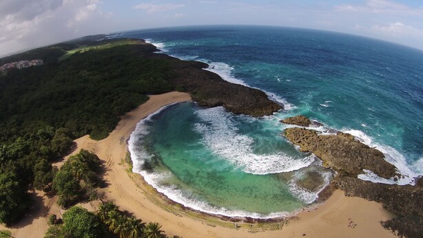 A coastal landscape with a sandy beach, clear turquoise waters, and rocky outcrops. - Tropical Caribbean Bungalow w/ Ocean Views & Pool (Manati)