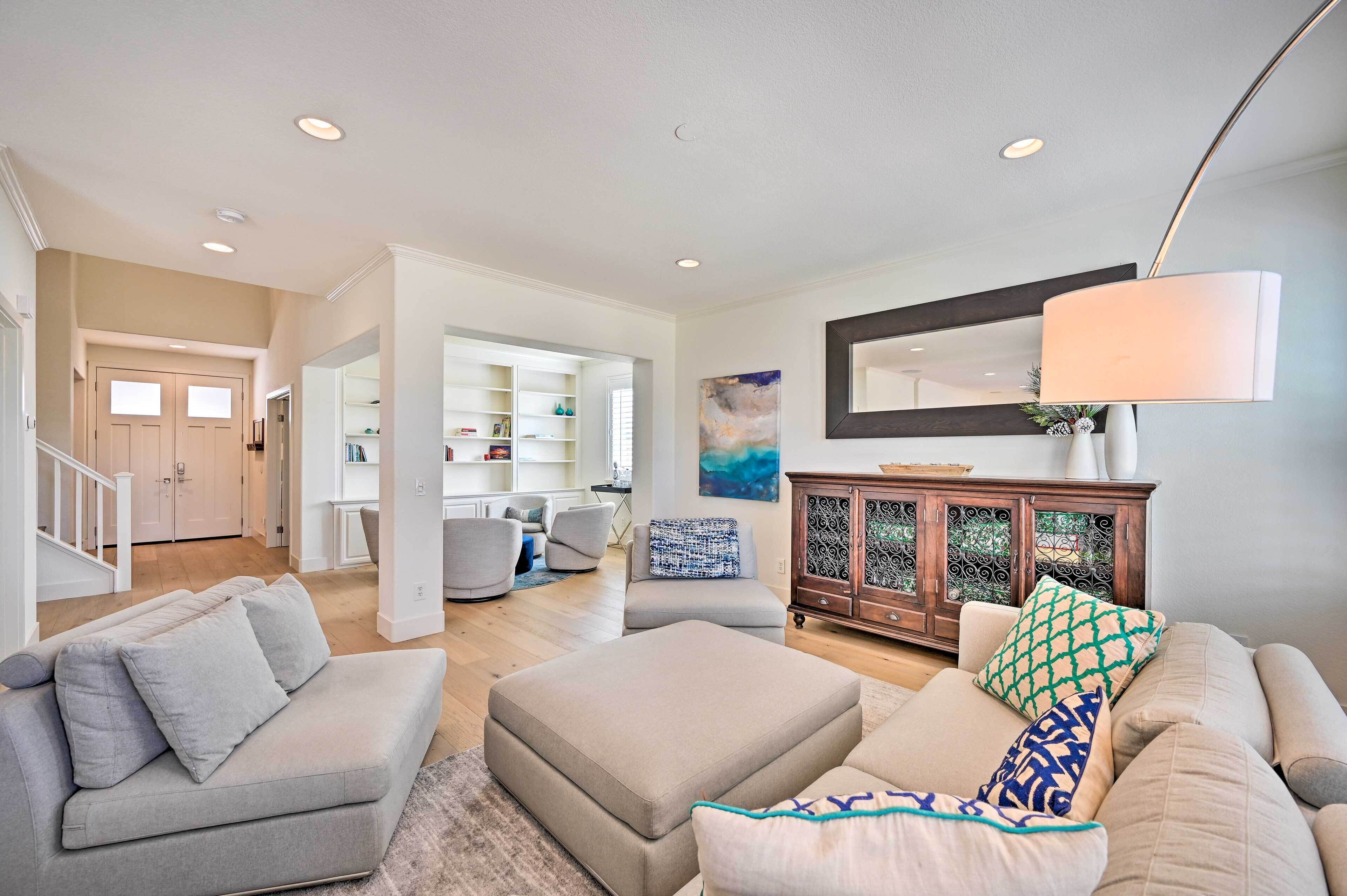 A spacious living room with a neutral color palette, a large sofa, a coffee table, and a cabinet with decorative items.