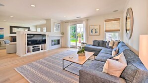 A modern living room with a large sectional sofa, a flat-screen TV, and a fireplace. - Stunning Carlsbad Gem w/ Fire Pit & Hot Tub! (Carlsbad)