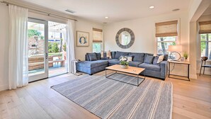 A modern living room with a sectional sofa, a coffee table, and a large window with blinds. - Stunning Carlsbad Gem w/ Fire Pit & Hot Tub! (Carlsbad)