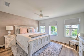 Un dormitorio con cama, mesitas de noche, cómoda y ventilador de techo.