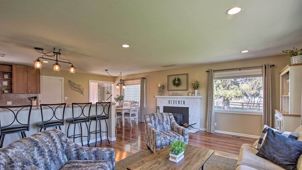 A spacious living room with a fireplace, a dining area with chairs, and a kitchen area with wooden cabinets. - Ellensburg Home w/ Mountain Views on 3 Acres! (Ellensburg)
