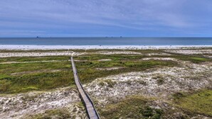 Un paisaje costero con un paseo de madera que conduce a una playa.