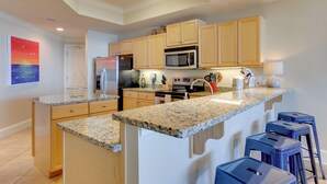 Una cocina moderna con encimeras de granito, armarios de madera y una isla central con taburetes de bar.
