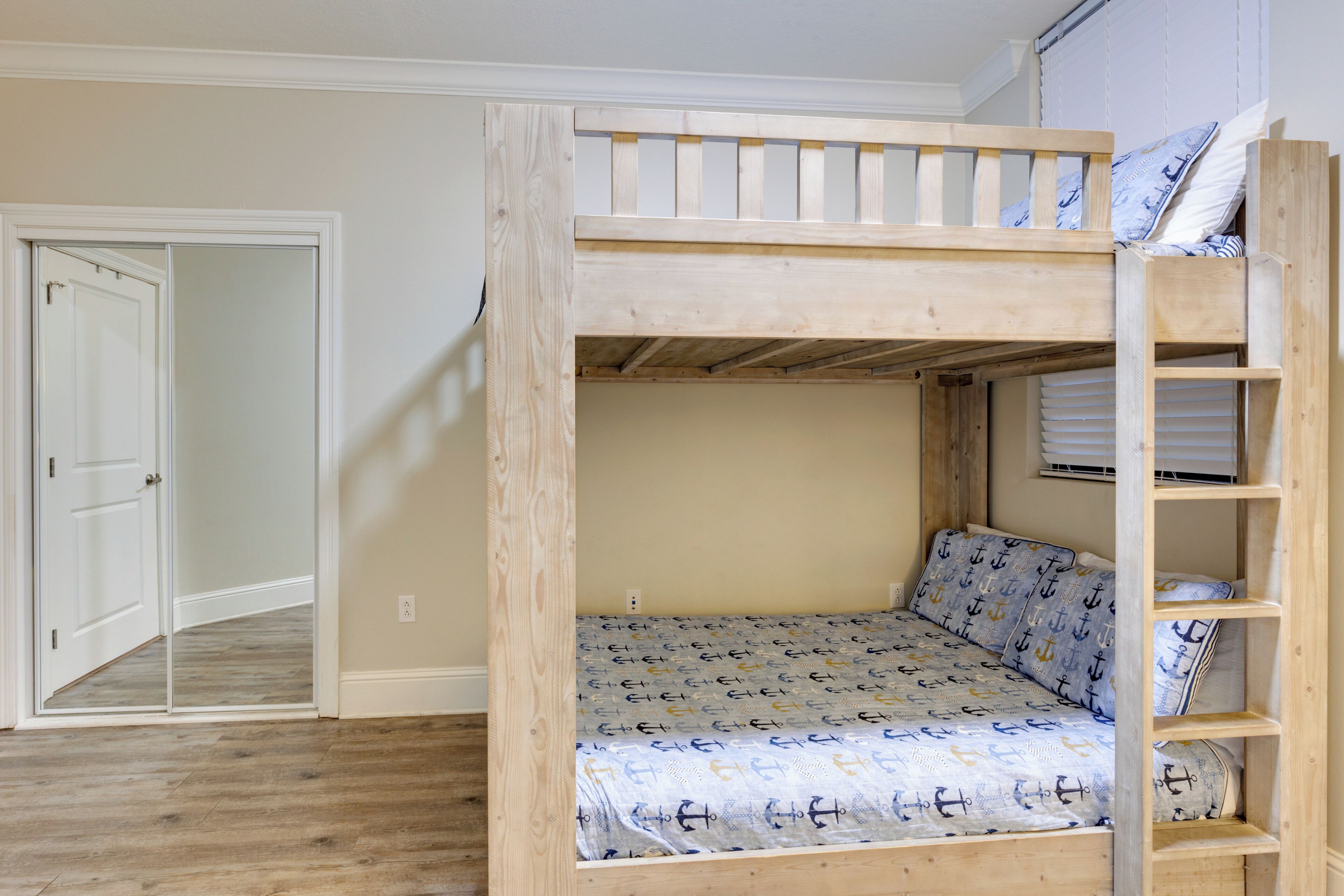 A bunk bed with a patterned mattress, a wooden ladder, and a door leading to another room.