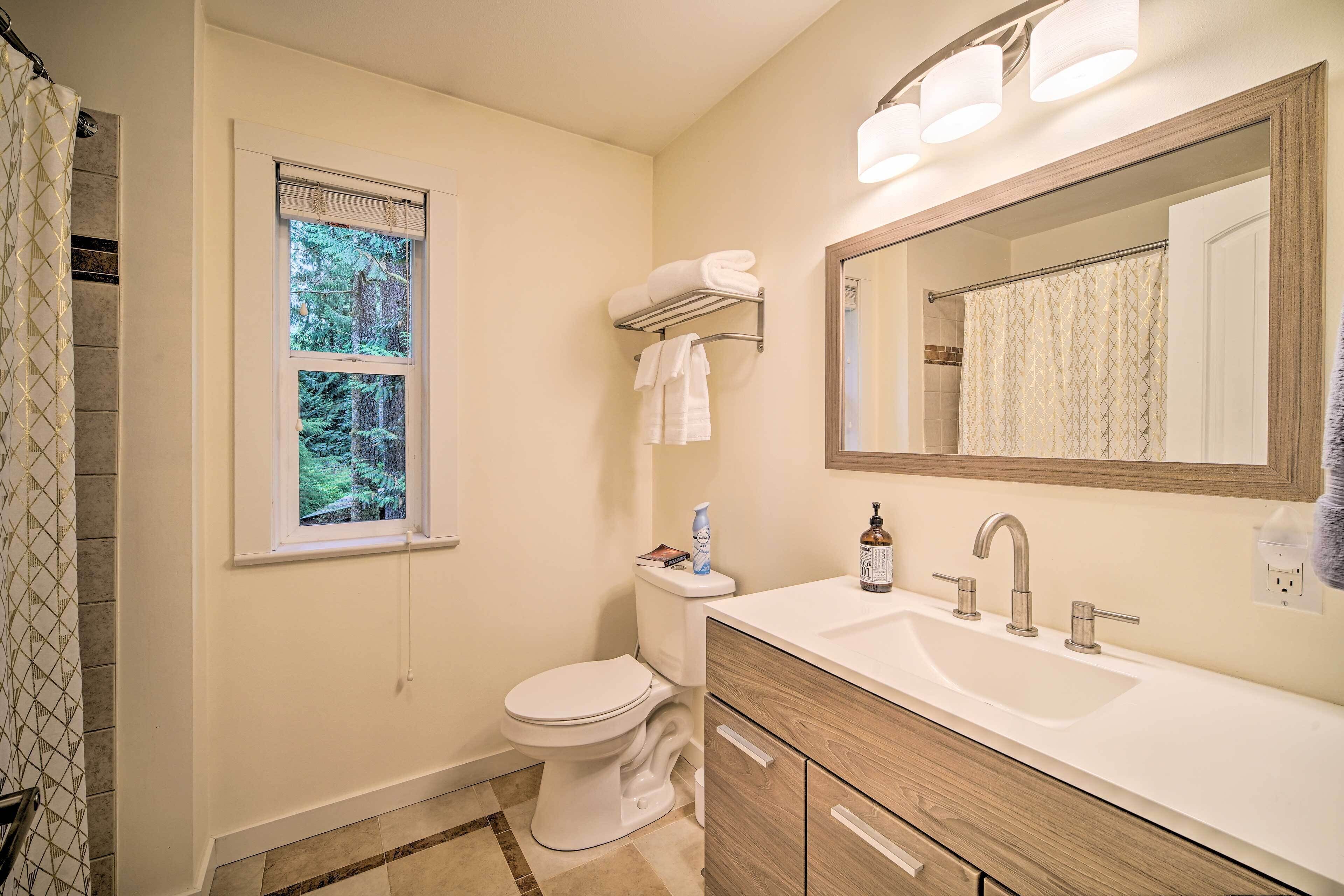 A bathroom with a toilet, sink, and window.