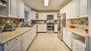 A modern kitchen with white cabinetry, a central island, a microwave, stove, and refrigerator. - Peaceful Forest Retreat by Mt. Baker Slopes! (Deming)