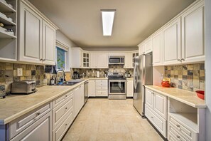A modern kitchen with white cabinetry, a central island, a microwave, stove, and refrigerator. - Peaceful Forest Retreat by Mt. Baker Slopes! (Deming)